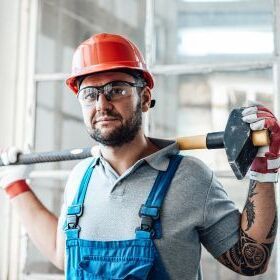 Montuer with red helmet and blue overalls with a hammer
