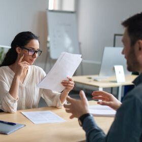 A female employee and a male employee discuss with papers in hand