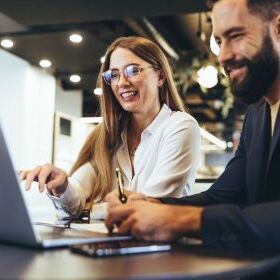 One female employee and one male employee work on the laptop