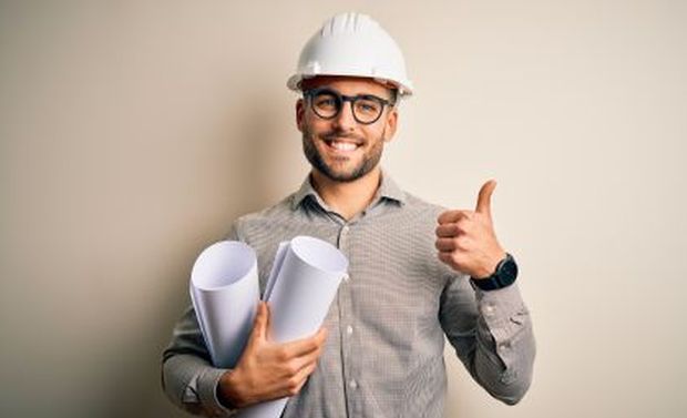 Ingenieur mit Helm und Plänen in der Hand